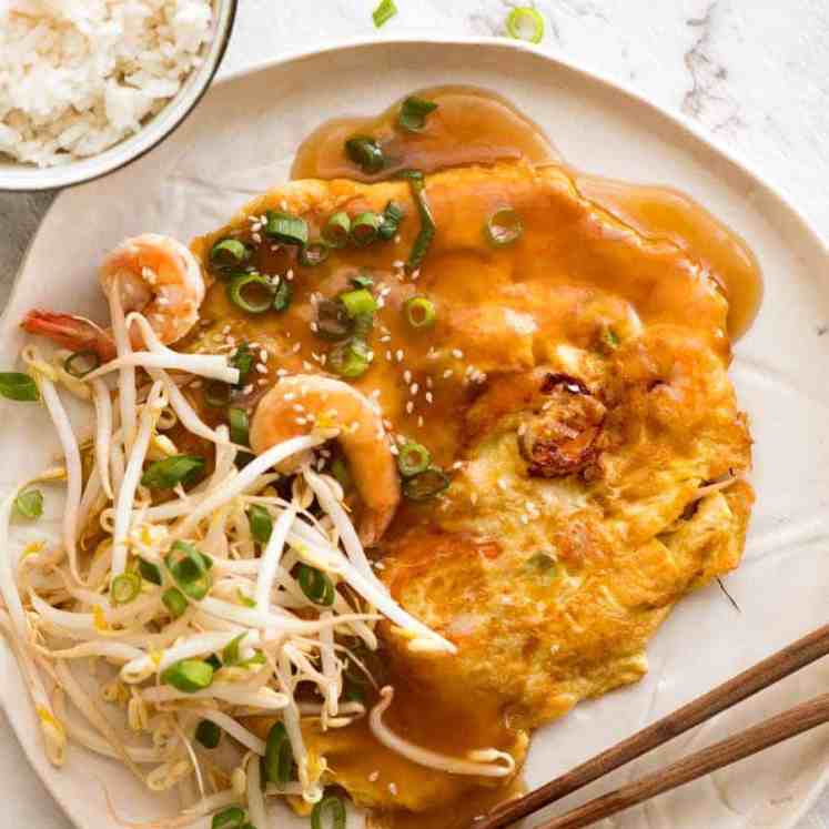 Overhead photo of Egg Foo Young on a rustic white plate with a side of rice, ready to be eaten