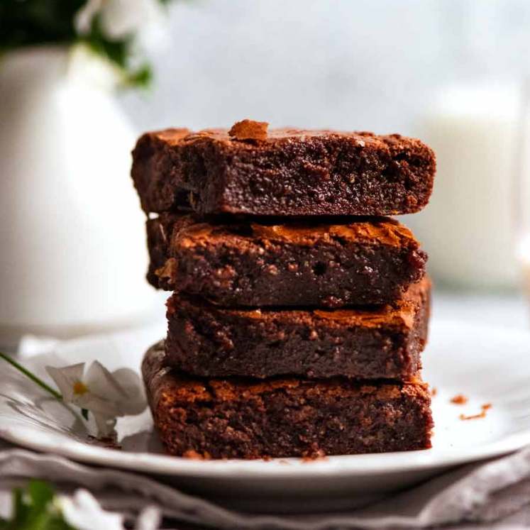 Stack of Flourless Chocolate Brownies (gluten free) slices with milk and flowers in the background